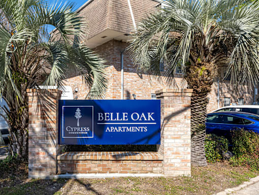 A sign for Belle Oak Apartments is displayed in front of a building.