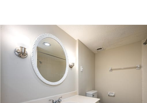 A bathroom with a white sink and a round mirror.
