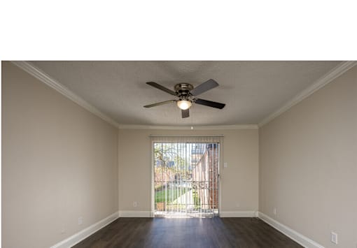 A room with a ceiling fan and sliding glass door.