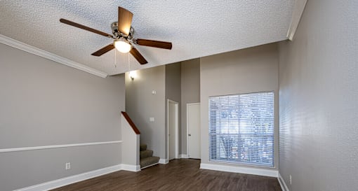 A room with a ceiling fan and a staircase.