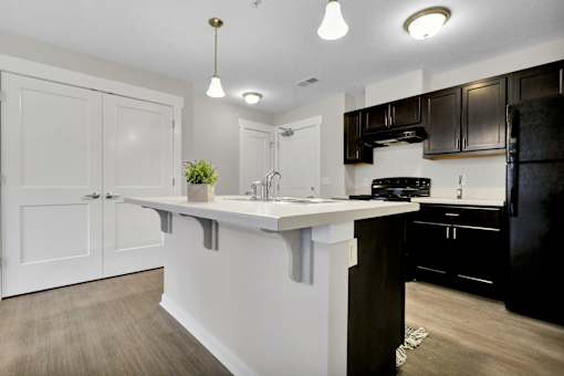 A kitchen with white cabinets and a black refrigerator.