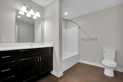 A white toilet sits in a bathroom with a white sink and a mirror.