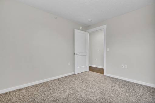 A room with a carpeted floor and a white door.