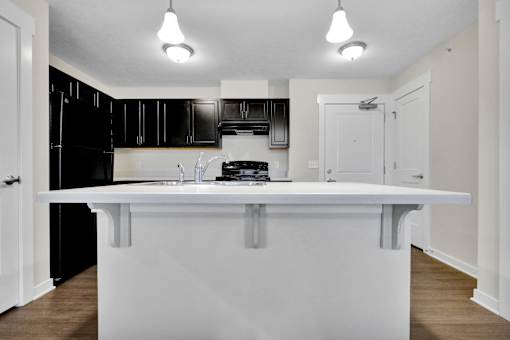 A white kitchen island with a black fridge and microwave.