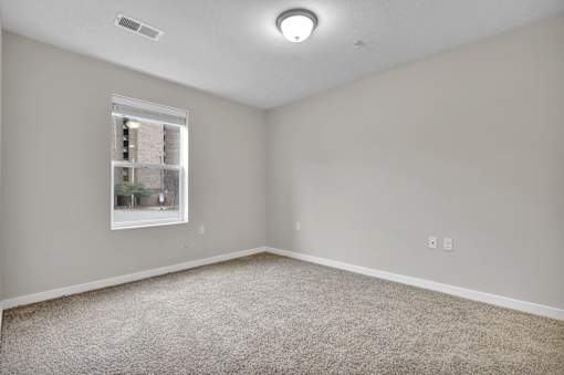 A room with a window and a carpeted floor.