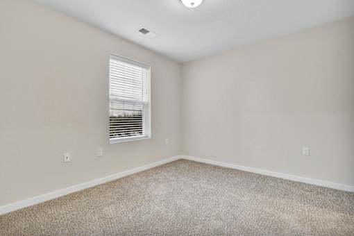 A room with a window and carpeted floor.