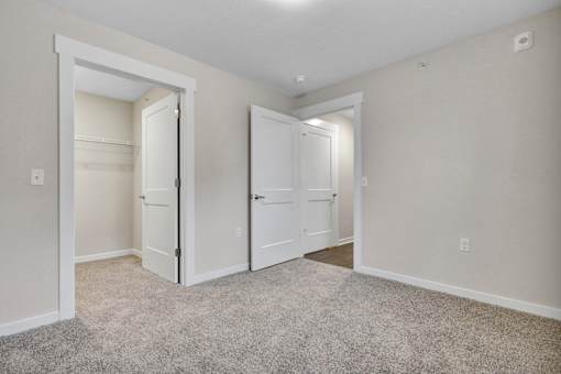 A room with two white doors and a carpeted floor.