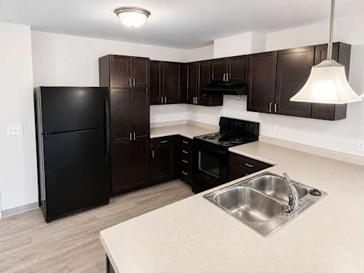 A kitchen with black appliances and brown cabinets.