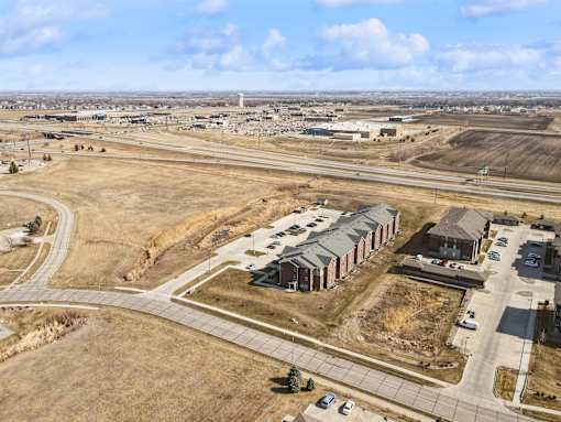 A large open field with a few buildings and cars.
