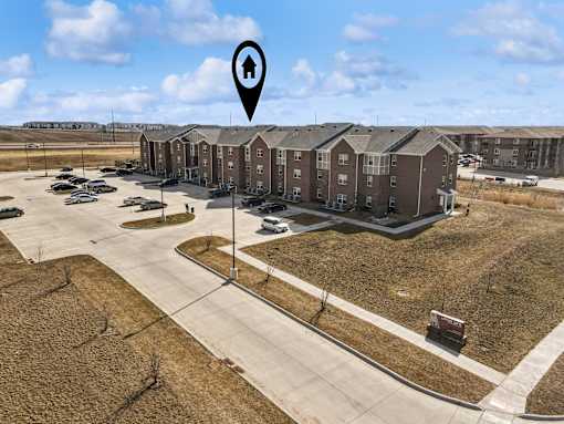 A large apartment complex with a parking lot in front.