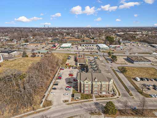 A large parking lot is surrounded by buildings and trees.