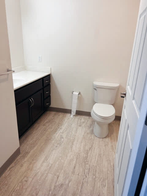 A white toilet sits in a bathroom with a white counter and a white towel rack.