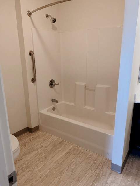 A white bathroom with a walk in shower and a toilet.