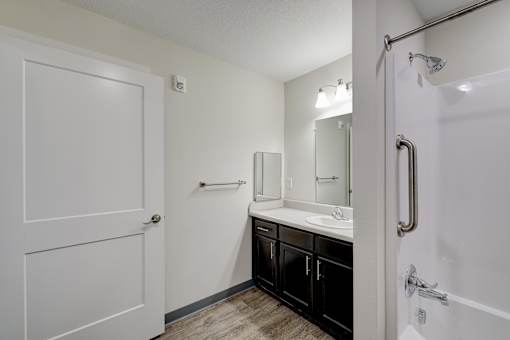 A white door opens to a bathroom with a sink and mirror.