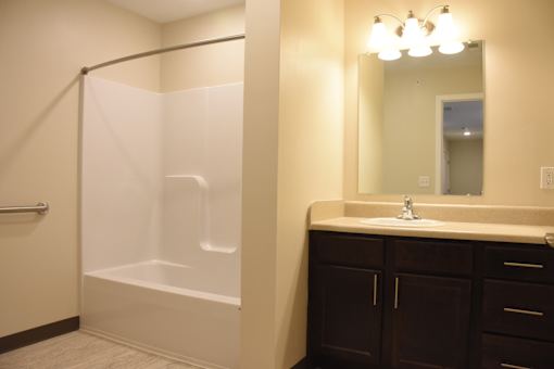 A bathroom with a white tub and brown cabinets.