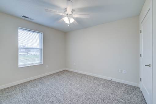 A room with a ceiling fan and carpeted floor.