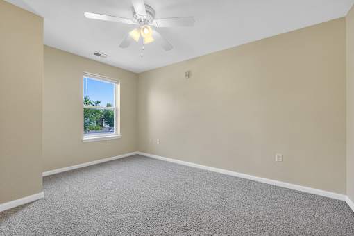 A room with a ceiling fan and carpeted floor.