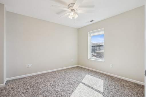 A room with a ceiling fan and a window letting in light.