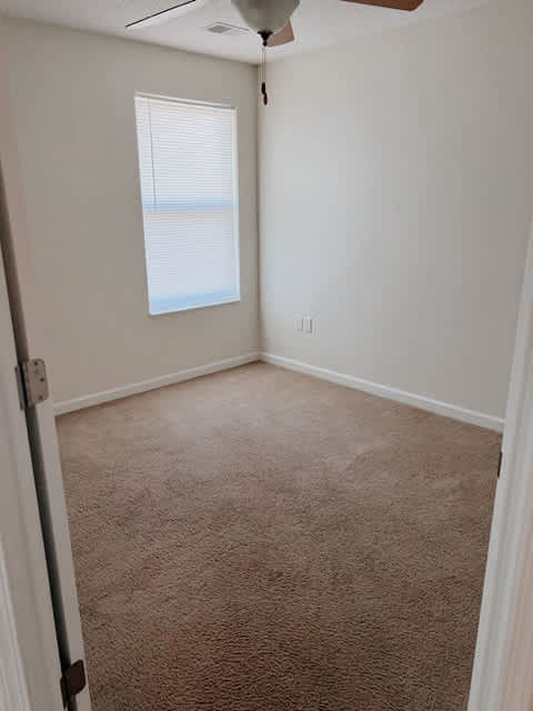 A room with a carpeted floor and a window with blinds.
