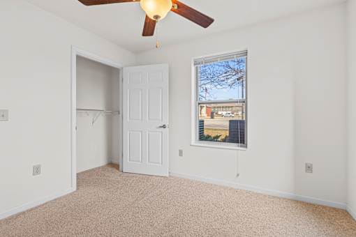 A room with a ceiling fan and a window overlooking a cityscape.