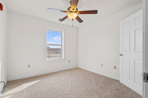 A room with a ceiling fan and a window overlooking a cityscape.
