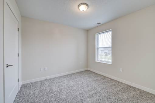 A room with a carpeted floor, a door, and a window.