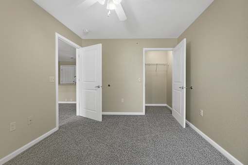 A room with a carpeted floor and two open doors.