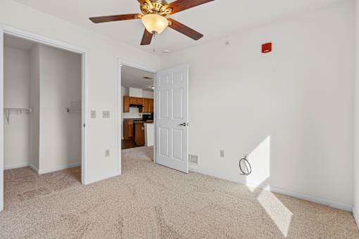 A room with a ceiling fan and carpeted floor.