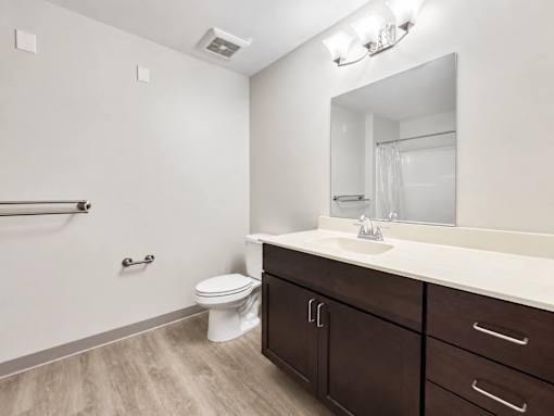 A bathroom with a toilet, sink, and mirror.
