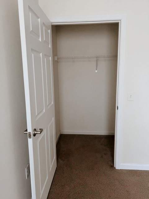 A white door is open to a room with a carpeted floor.