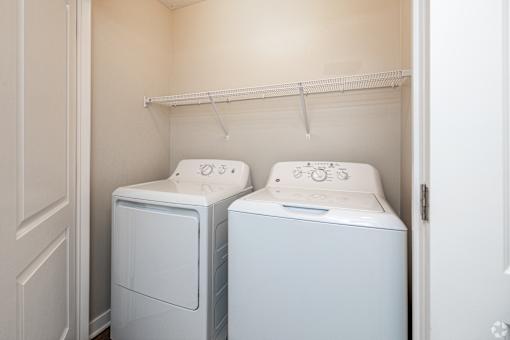 Two white front loading washing machines in a small laundry room.