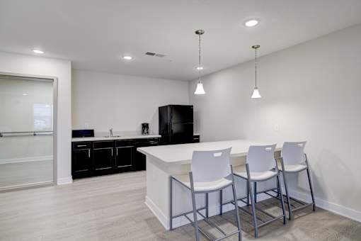 A kitchen with white chairs and a black fridge.
