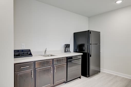 A kitchen with a black fridge and a white sink.