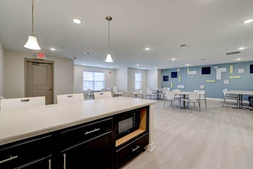 A kitchen with a white counter top and black drawers.