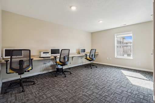 A room with four chairs and four computers.