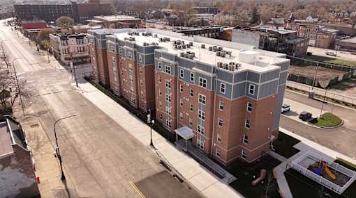 A large building with a lot of windows is in the middle of a street.