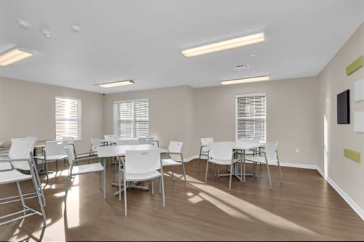 A room with white chairs and tables is empty.