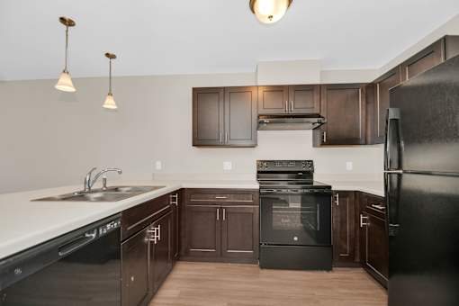A modern kitchen with dark brown cabinets and black appliances.