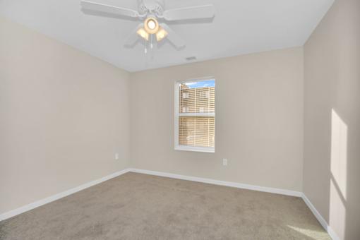 A room with a ceiling fan and a window with blinds.