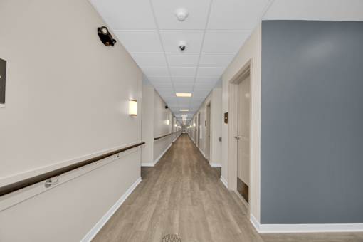 A long hallway with doors on the right and lights on the ceiling.