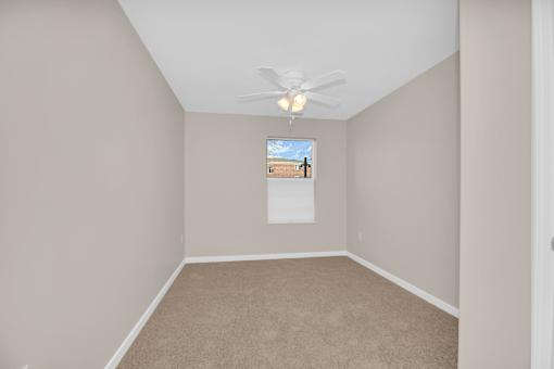 A room with a ceiling fan and a window.