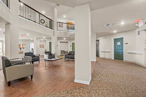 A spacious living room with a staircase and a green door.