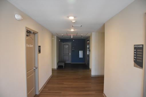 A hallway with a door on the left labeled "Fire Alarm" and another door on the right labeled "Office Hours".