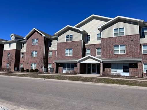 Apartment building with red brick and beige siding.