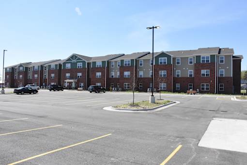 A parking lot in front of a large apartment complex.