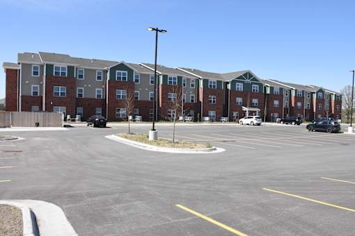 A parking lot in front of a large apartment complex.