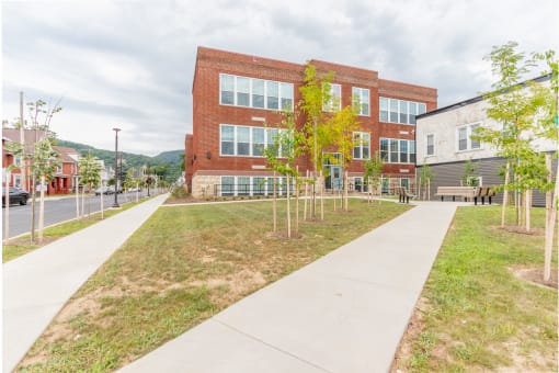 a sidewalk in front of a brick building with trees