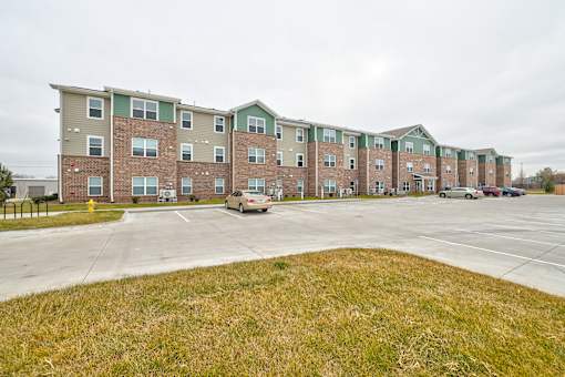 Apartment complex with a parking lot in front.