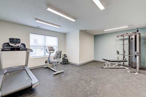 A spacious gym with a treadmill, weight bench, and other exercise equipment.