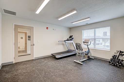 A spacious room with a treadmill, exercise equipment, and a door.